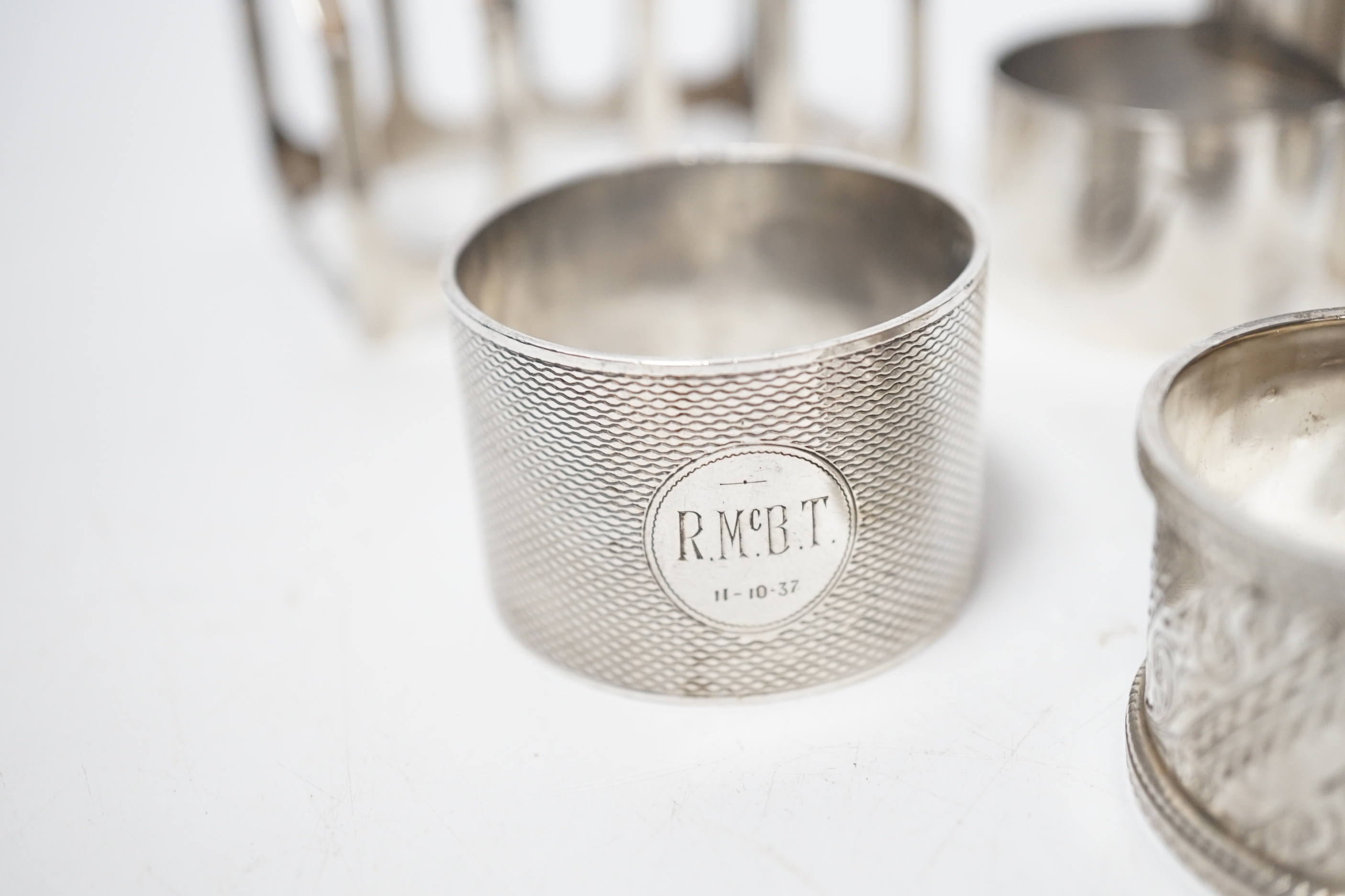 A set of six silver napkin rings, Robert Pringle & Sons, London, 1953, two other silver napkin rings and a silver five bar toast rack, 9.8oz.